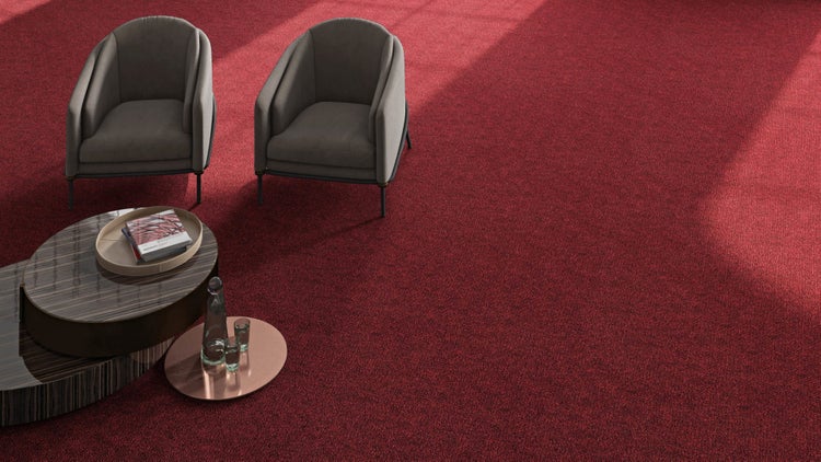 Modernes Wohnzimmer mit zwei grauen Sesseln und einem Holztisch auf einem großflächigen, roten Teppichboden.