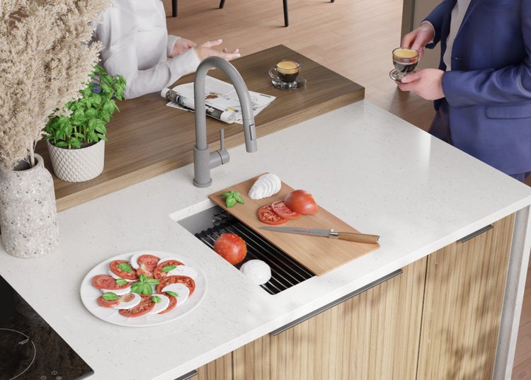 Küchenspüle mit Schneidebrett, Messer, Tomaten und Mozzarella auf einer Küchentheke
