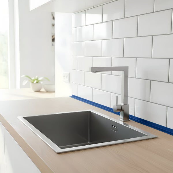 Moderne Küchenspüle aus Edelstahl mit passender Küchenarmatur in einer hellen Küche mit weißen Wandfliesen und Arbeitsplatte in Holzoptik