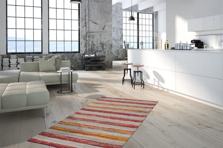 Moderner Wohnbereich im Industriestil mit hellem Holzboden, gestreiftem Teppich, hellem Sofa und offener Küche mit Kochinsel.