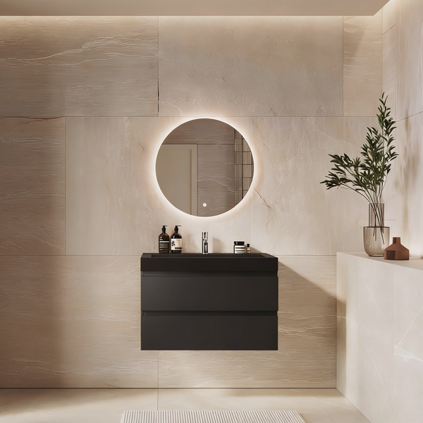 Modernes Badezimmer mit hängendem Waschtisch in Schwarz und beleuchtetem Rundspiegel vor hellen Natursteinfliesen.