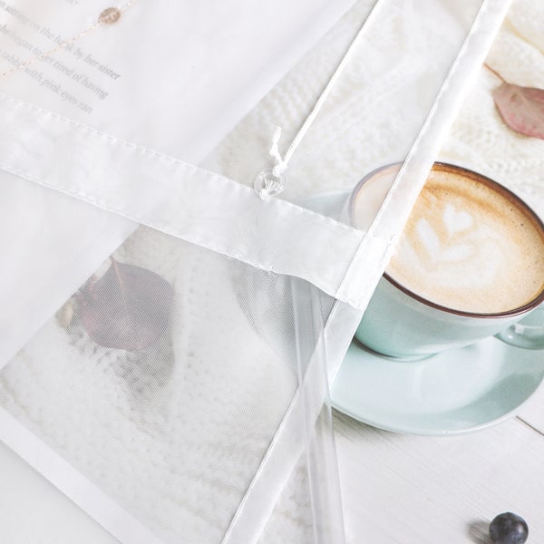 Szene mit Gardine, Tasse Kaffee, Herbstblatt und Strickdecke