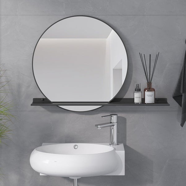 Runder Badezimmerspiegel mit Ablage und Wandwaschbecken vor einer Fliesenwand mit Armatur und Dekoration