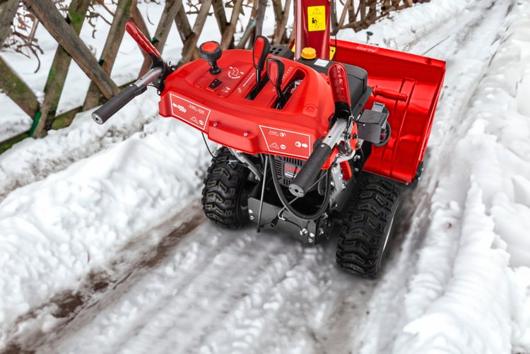 AL-KO Schneefräse mit Bedienfeld und Profilreifen auf einem verschneiten Weg.
