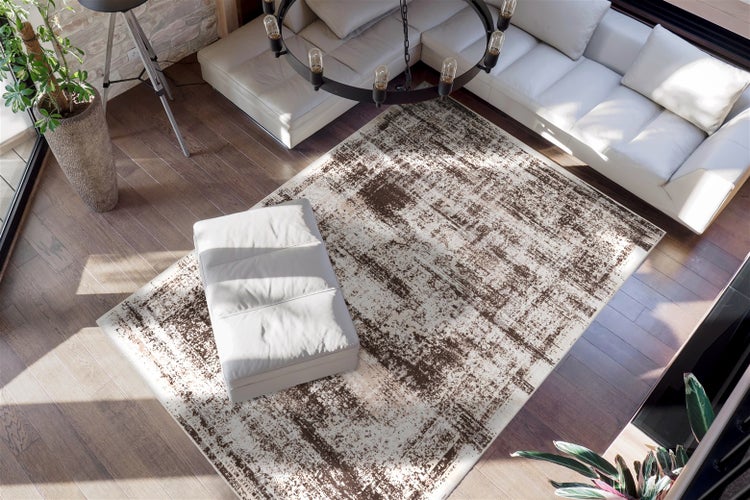 Rechteckiger Webteppich mit abstraktem, antikem Muster in Braun und Creme im modernen Wohnzimmer auf Holzboden unter weißem Sofa.