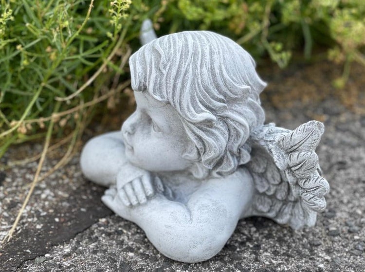 Gartenfigur Engelskind aus Stein in liegender Position zur Dekoration im Garten.