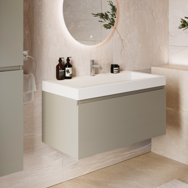 Moderner Waschtisch mit Unterschrank in einem Badezimmer mit Steinoptik Wandfliesen, beleuchtetem Rundspiegel und Armatur.