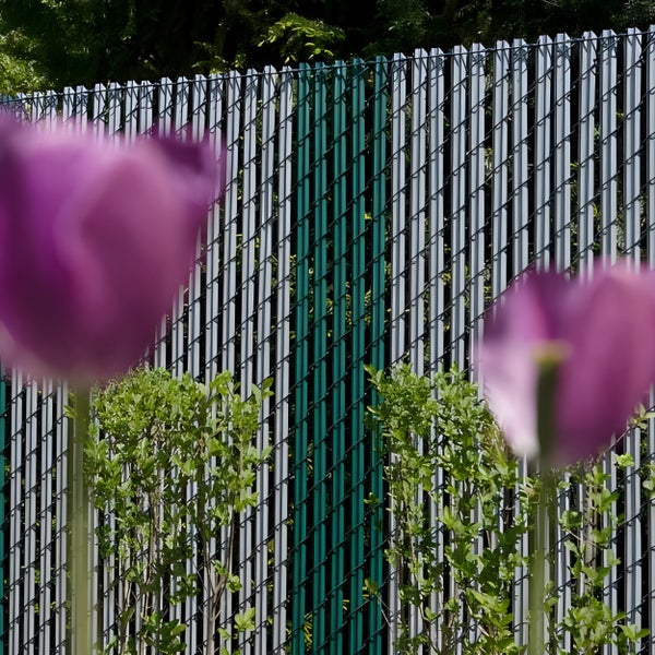 Sichtschutzzaun mit grünen und grauen Lamellen im Garten