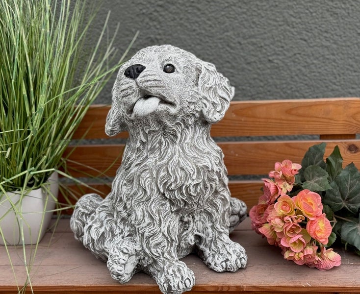 Gartenfigur in Form eines sitzenden Welpen mit herausgestreckter Zunge in Steinoptik auf einer Holzbank