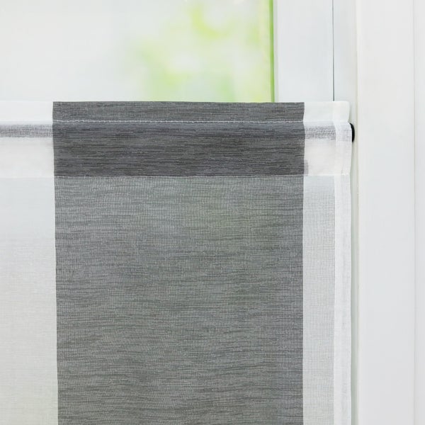 Detailansicht eines grauen und weißen Rollos vor einem Fenster
