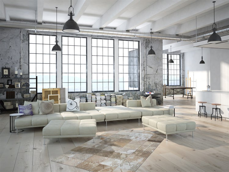 Helles Wohnzimmer im Industriestil mit großem Modulsofa, Holzfußboden und Sichtbetonwänden. Große Fensterfronten und industrielle Pendelleuchten.