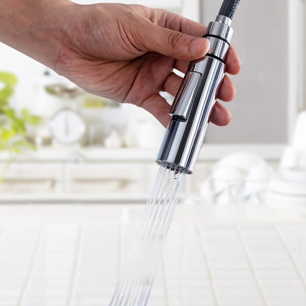 Hand hält ausziehbare Küchenarmatur mit herauslaufendem Wasserstrahl