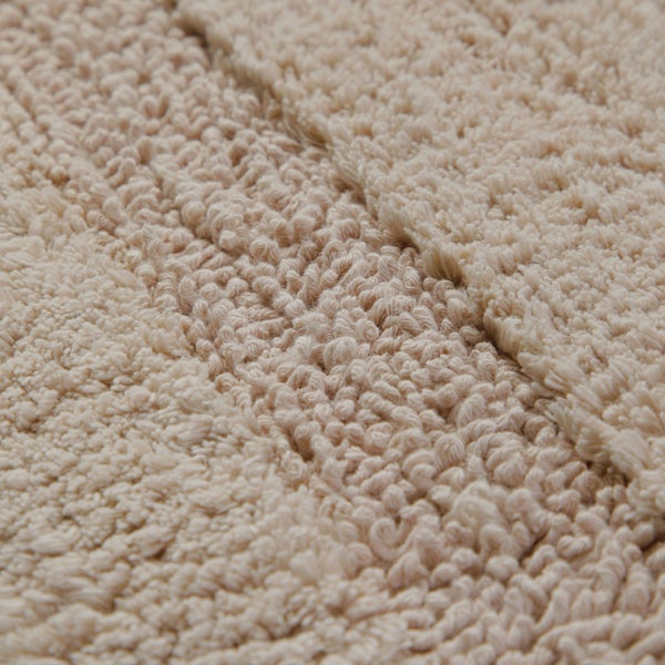 Nahaufnahme der weichen Oberflächenstruktur einer Badematte mit Schlingen- und Rippenmuster.