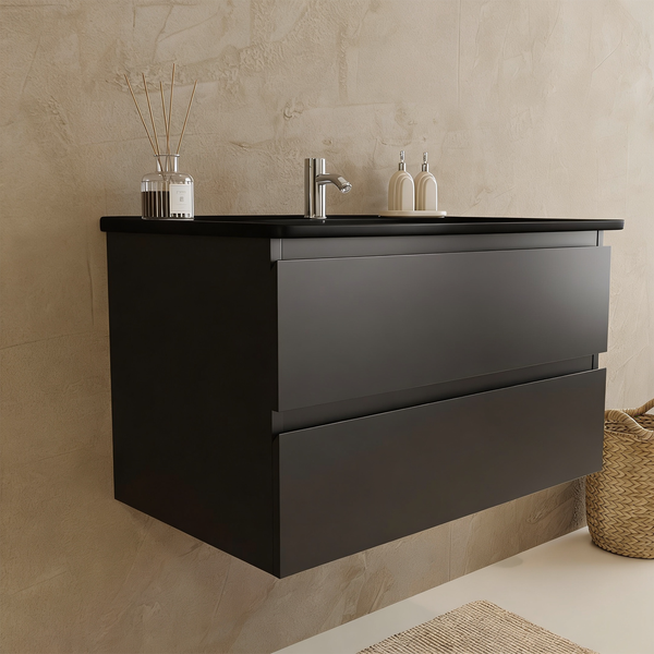 Moderner dunkler wandhängender Waschtischunterschrank mit zwei Schubladen, integriertem Waschbecken und Armatur in einem minimalistischen Badezimmer.