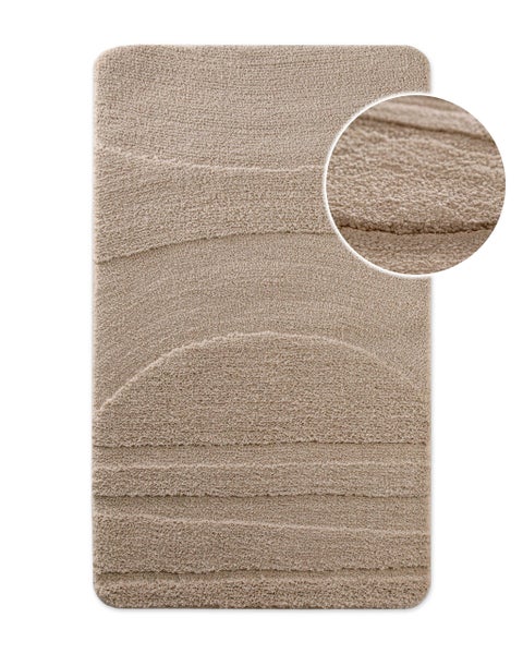 Beige Badematte mit Reliefmuster aus Linien und einem Halbkreis, weiche Textur mit Detailansicht.