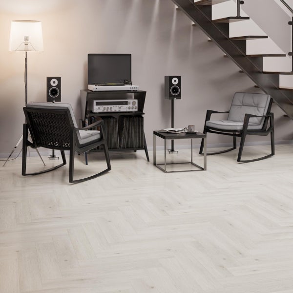 Wohnzimmer mit hellem Fischgrätparkett, zwei Schaukelstühlen, einem Plattenspieler und Lautsprechern unter einer Treppe.