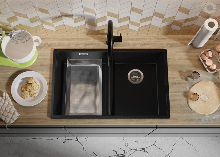 Schwarzes Spülbecken mit Abtropffläche und Küchenutensilien auf einer Küchentheke.