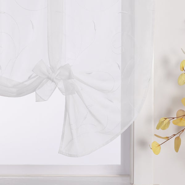 Gardine mit Schleife und floralem Muster vor einem Fenster