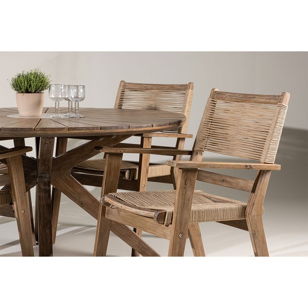 Gartensitzgruppe mit rundem Holztisch, geflochtenen Stühlen, Pflanze und Gläsern