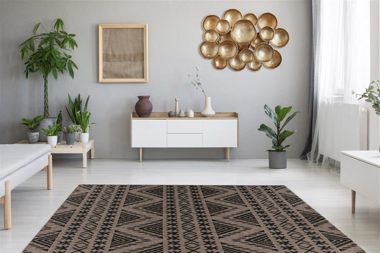 Modernes Wohnzimmer mit geometrischem Teppich, weißem Sideboard, Pflanzen und goldener Wanddekoration an grauer Wand. Hell und geräumig.