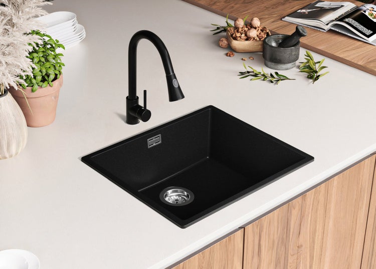 Schwarzes Spülbecken mit schwarzem Wasserhahn in einer Küchenszene.