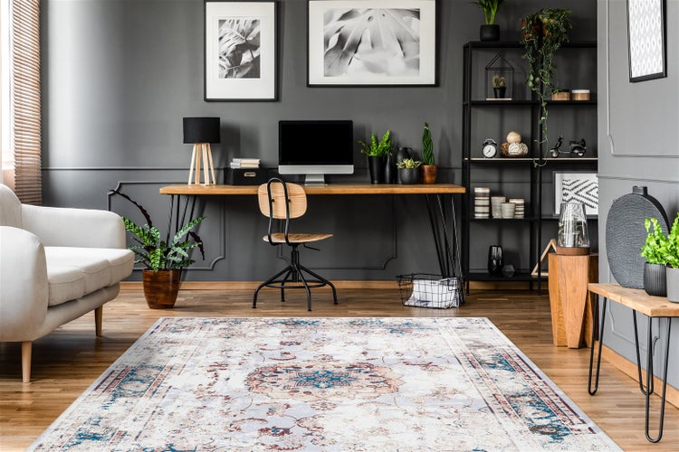 Großer rechteckiger Teppich mit Vintage-Orient-Muster in einem modernen Arbeitszimmer mit Holzschreibtisch, Computer und grauen Wänden.