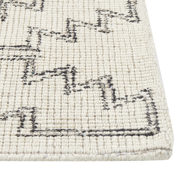 Wollteppich in Creme mit schwarzem geometrischem Muster, Detailansicht der Textur und Webkante.