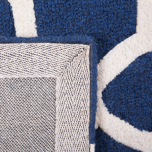 Detailansicht eines blauen Teppichs mit weißem Muster und gewebter Rückseite