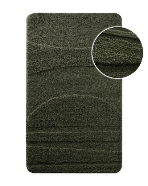 Dunkelgrüner Badteppich mit strukturiertem Wellenmuster und Detailansicht der weichen Textur.