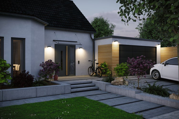 Moderne Hauseingangsszene bei Abenddämmerung mit beleuchteter Fassade, Garage, Fahrrad und gepflastertem Vorgartenbereich.