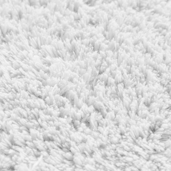 Detailansicht eines weißen Hochflor-Teppichs mit weicher Struktur.