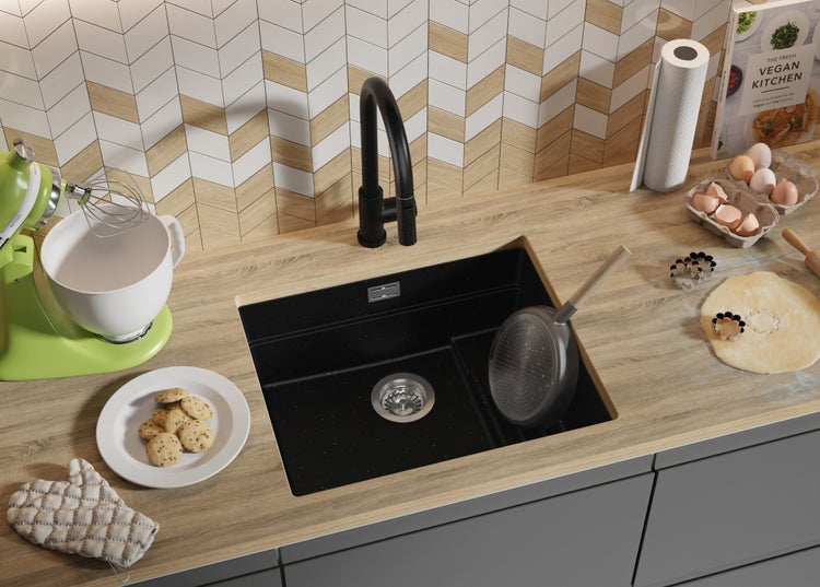 Küchenszene mit Spüle, Armatur, Arbeitsplatte, Küchenmaschine, Kochbuch und Backutensilien.