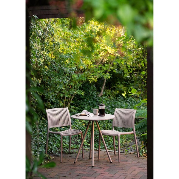 Gartenszene mit Tisch, zwei Stühlen, Kaffeekanne und Geschirr auf einer Terrasse