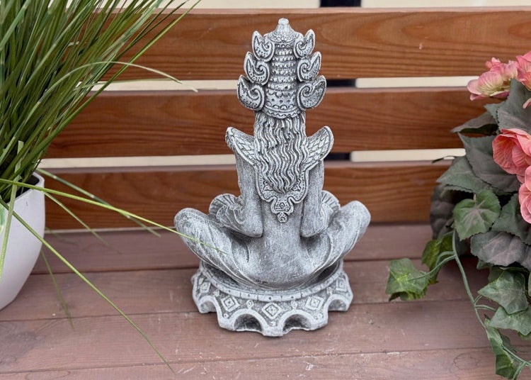 Gartenfigur aus Steinguss in meditierender Haltung, Rückansicht mit detailreichem Kopfschmuck, platziert auf Holzfläche.