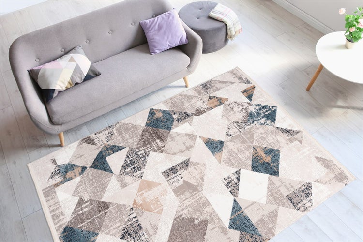 Moderner Wohnbereich mit Teppich mit geometrischem Dreiecksmuster, grauem Sofa und hellem Holzboden.