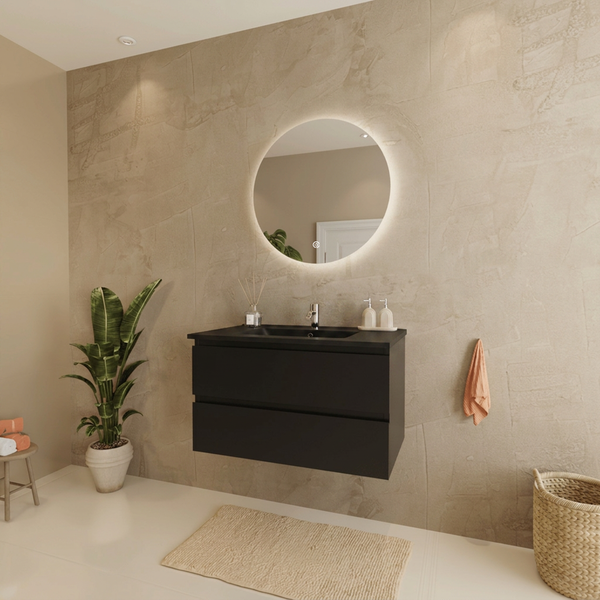 Modernes Badezimmer mit hängendem schwarzem Waschtischunterschrank, rundem LED-Spiegel und beige strukturierter Wand.
