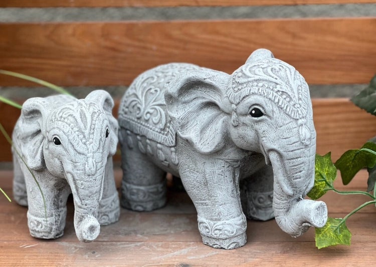 Zwei dekorative Gartenfiguren in Form von verzierten Elefanten aus Steinguss, ein großer und ein kleiner Elefant.