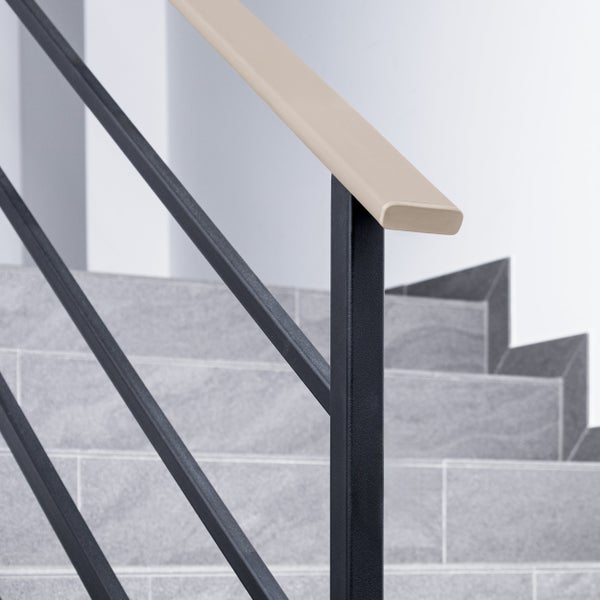 Modernes Treppengeländer aus dunklem Metall mit diagonalen Streben und hellem Handlauf auf grauen Steinstufen.