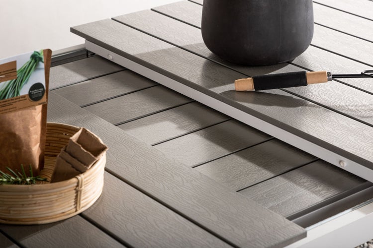 Szene mit Pflanzgefäßen, Saatgut, Pflanzschalen, Handrechen und Dekoration auf einem Tisch.