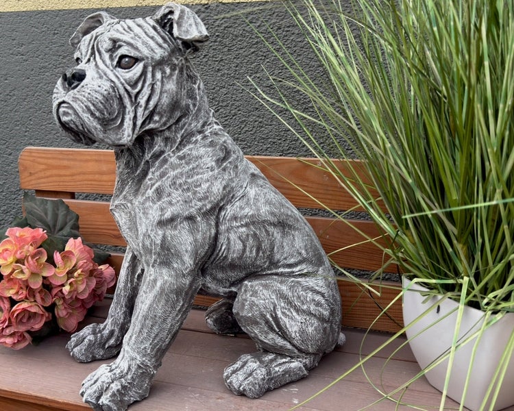 Detailreiche Gartenfigur Hund Bulldogge aus Steinguss für die Außendekoration auf einer Bank platziert.