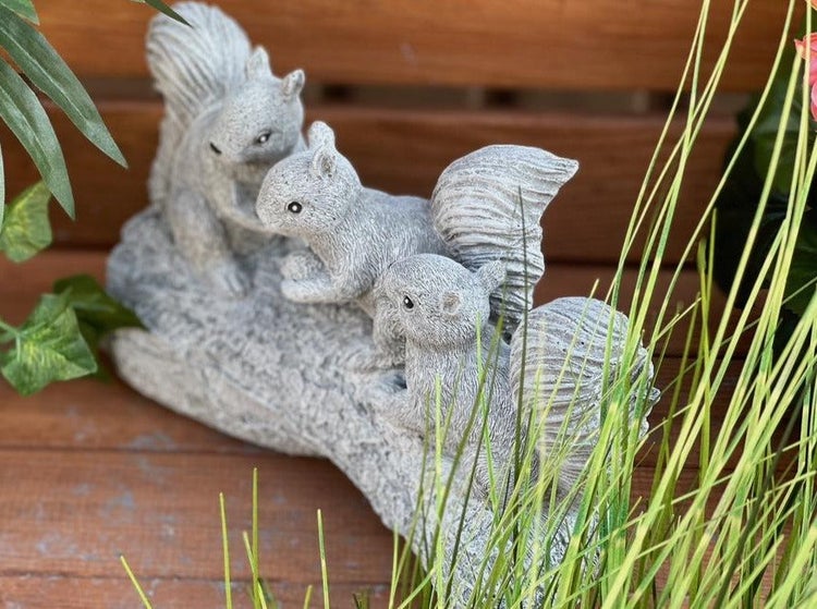 Gartenfigur Eichhörnchen Gruppe auf einem Baumstamm aus Steinguss für die Gartendekoration.
