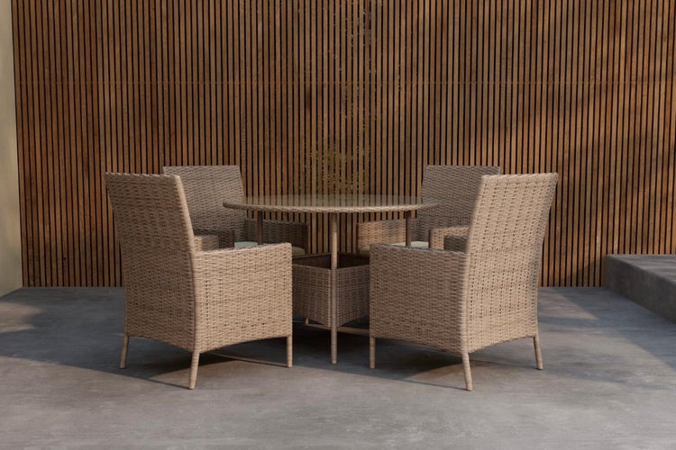 Gartenmöbel-Set aus Polyrattan mit einem runden Glastisch und vier Sesseln vor einer Lamellenwand aus Holz.