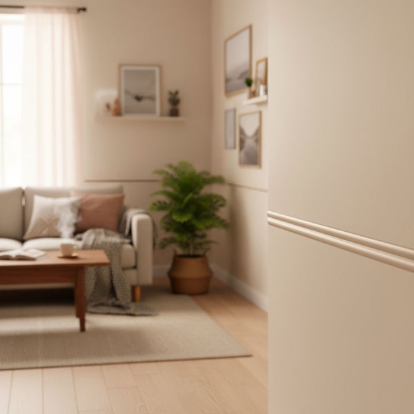 Wohnzimmer mit Zierleisten an der Wand, Sofa, Tisch und Dekorationen für eine gemütliche Atmosphäre.