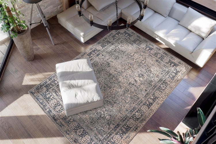 Hell gestalteter Wohnraum mit großem Orientteppich im Vintage-Stil auf Parkettboden, weißem Ledersofa, Hocker und modernem Kronleuchter.