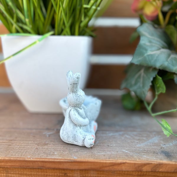 Dekorative Osterhasenfigur aus Steinoptik für die Gartendekoration auf einem Holzregal