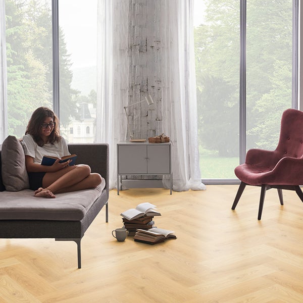 Wohnzimmer mit Fischgrätparkett, Sofa und Leseecke.