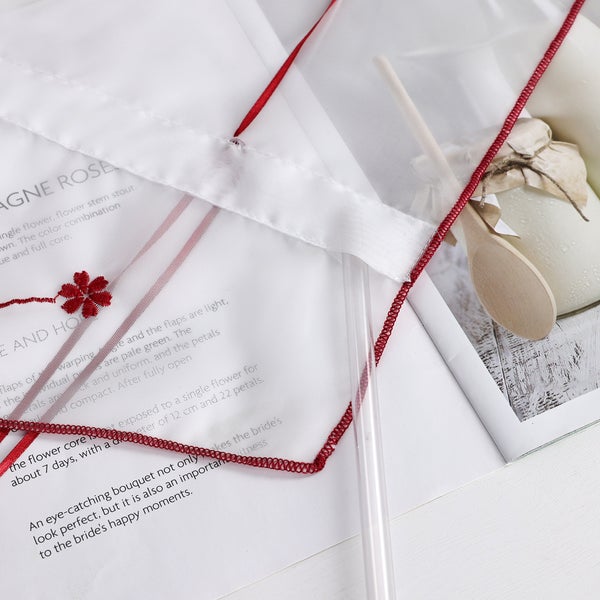 Nahaufnahme eines Brautschleiers mit roter Bordüre und Blumenmuster