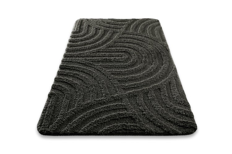 Grüner Frosch mit Krone zeigt auf die Materialangabe 100 Prozent Polyester auf einem grauen Teppich.
