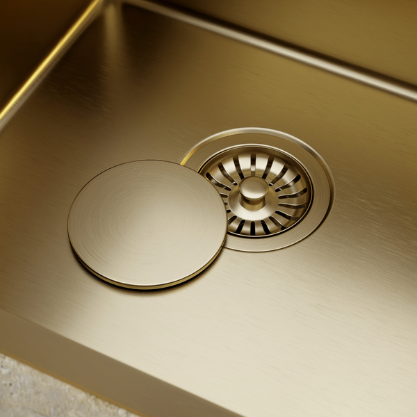 Küchenspüle aus Metall mit Siebkorbventil und runder Abdeckung in gebürsteter Optik.