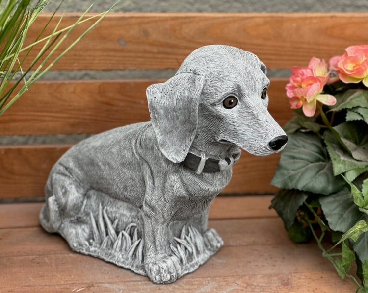 Gartenfigur Dackel aus Steinguss, grau, sitzend.